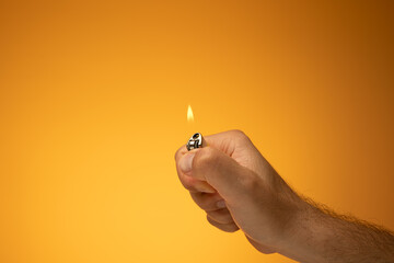 Lit cigarette lighter and flame held in hand by Caucasian male hand. Close up studio shot, isolated...