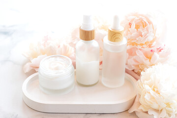 Fototapeta na wymiar composition with cosmetic products, mockup white jars and bottles and white peonies on a marble background