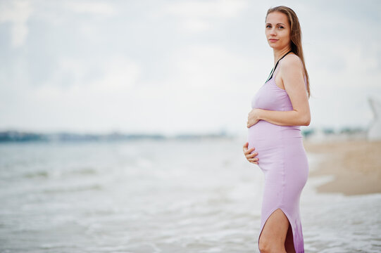Summer vacations. Pregnant mother on sea sand beach.