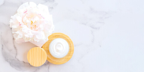 top view of collagen face cream in glass jar with bamboo cap on marble background. Skin care codmetic product banner