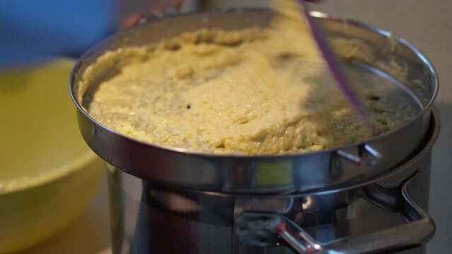 Close Up Of Potato Dough Lumps Dropping Onto Boiling Water In Pot Using Spaetzle Maker. Making Bryndzove Halusky Dumplings.