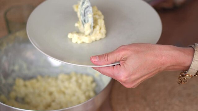Plating Prepared Bryndzove Halusky, Slovak Food Made Of Boiled Potato Dough Lumps (Halusky) And Soft Sheep Cheese (Bryndza), Topped With Smoked Pork Fats. close up