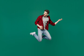 Full body young happy expressive singer caucasian man he 20s wearing red shirt grey t-shirt play guitar rock musician isolated on plain dark green background studio portrait. People lifestyle concept.