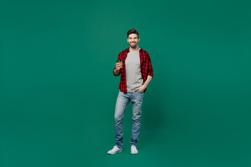 Fototapeta na wymiar Full body young happy smiling fun caucasian man he 20s wearing red shirt grey t-shirt hold takeaway delivery craft paper brown cup coffee to go isolated on plain dark green background studio portrait