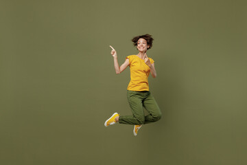 Full body young happy woman she 20s wear yellow t-shirt jump high indicate point index finger on...