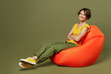 Full body young smiling cheerful fun cool happy woman she 20s wear yellow t-shirt sit in bag chair...
