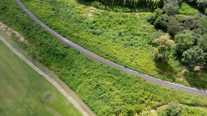 Aerial view of a drone on a railway track in a rural landscape with green forest during the rainy...
