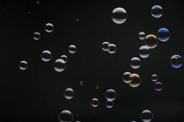 Flying soap bubbles on black background. Abstract soap bubbles with colorful reflections. Soap bubbles in motion background.