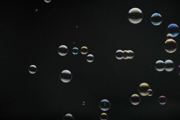 Flying soap bubbles on black background. Abstract soap bubbles with colorful reflections. Soap...