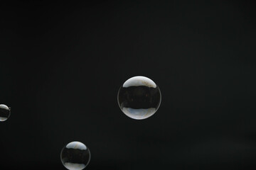 Flying soap bubbles on black background. Abstract soap bubbles with colorful reflections. Soap bubbles in motion background.