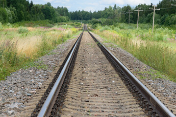 Fototapeta na wymiar beautiful railroad tracks leading into the distance with green grass and trees along the sides