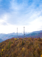 Obraz premium Drone view of two high-voltage towers with antennas in the forest in the mountains on an autumn day. Vertical photo