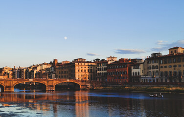 Obraz premium Bridge over the Arno river in Florence, with many tourists waiting for the sunset. The moon is already in the sky.