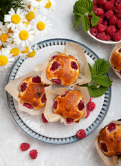muffins with raspberries on a light table decorated in a summer style. concept home baking, summer baking, holiday, summer tea party, dessert, summer desserts, romantic evening, valentine's day