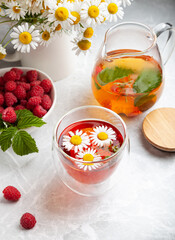 herbal tea with chamomile and berries on a light table in a summer style. the concept of tea drinking, herbal tea, proper nutrition, healthy drink