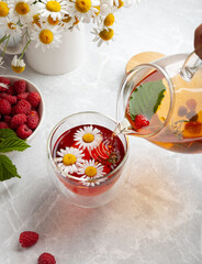 herbal tea with chamomile and berries on a light table in a summer style. the concept of tea...