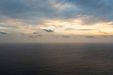 Blue sea and sky with clouds at sunset.