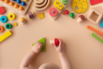 Toddler activity for motor and sensory development. Baby hands with various colorful wooden toys on table top view.