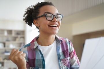 Excited african american teen girl in glasses celebrate victory, enjoy success, personal achievement