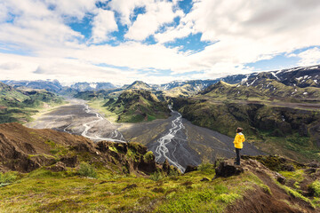 Valahn&uacute;kur viewpoint with female hiker standing on peak and krossa river flowing through in icelandic highlands at Th&oacute;rsm&ouml;rk, Iceland