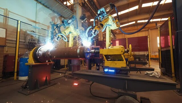 Modern welding automated machine welds metal with bright sparks in production plant workshop. Smart industry robot arms modernization for digital factory technology. IOT software control operation.4K
