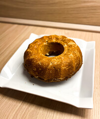 The pound cake from zucchini on the white plate with wooden background.