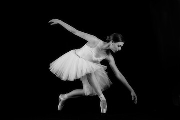 Ballet dancer on a black background. The dancer in a dance. Ballet pose. Dancer in a white dress