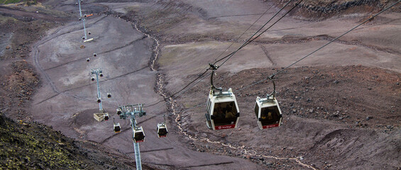 cable car with ascending cabin and above the valley and slope and mountains in Elbrus cloudy day