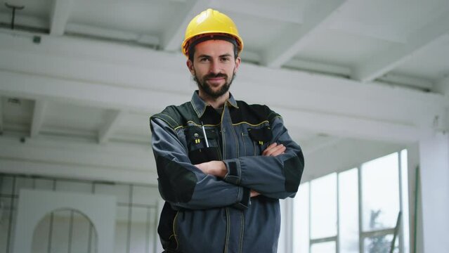 In front of the camera posing charismatic attractive constructor worker man with safety helmet he crossing hands and smiling cute