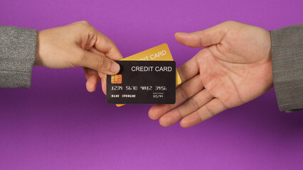 Hands are sent and receive black and gold credit cards on purple background.