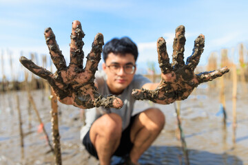 A young Asian teenage boy showing dirty hands after planting a tree with a happy and proud face - 519747435