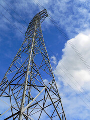 Power electricity lines against a bright blue sky with clouds