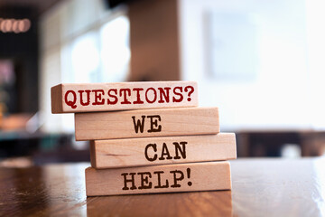Wooden blocks with words 'Questions? We can help'. Business concept