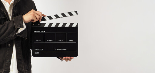 Body part of a man is holding black clapperboard or movie slate on white background. Studio shooting