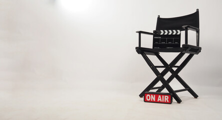 Black director chair and black clapper board on the chair and on air box on white background