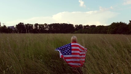 Young happy woman waving USA stars and stripes flag in golden sunset sunshine field