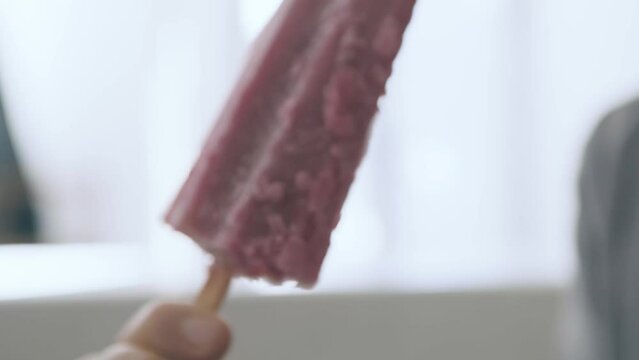 Slow motion detail of a girl eating a blueberry popsicle