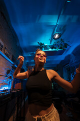 Beautiful female DJ dancing to techno in a small club