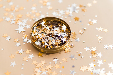 golden confetti in tin jar on beige background