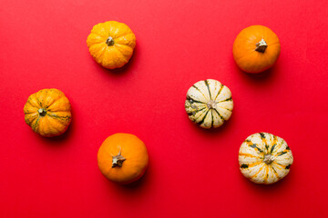 Obraz na płótnie Canvas Autumn composition of little orange pumpkins on colored table background. Fall, Halloween and Thanksgiving concept. Autumn flat lay photography. Top view vith copy space