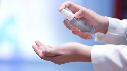 woman spraying her hands with sanitizer gel, spray outdoors, anti bacteria ,preventing the spread of bacteria or virus, blurred background, close up shot, hygiene, infection control,covid-19 concept.