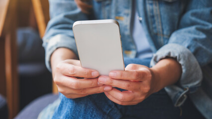 Closeup image of a woman holding and using mobile phone
