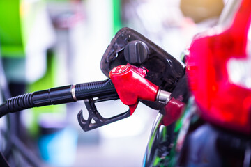 Selective focus to old red fuel nozzle with blurry fuel dispenser in gas station. Fill up fuel at...