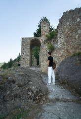 Tourist man with backpack exploring ruins of old city of Mystras, UNESCO world heritage...
