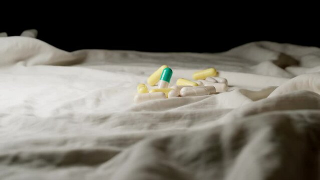 SLOW: Many pills fall on a bed