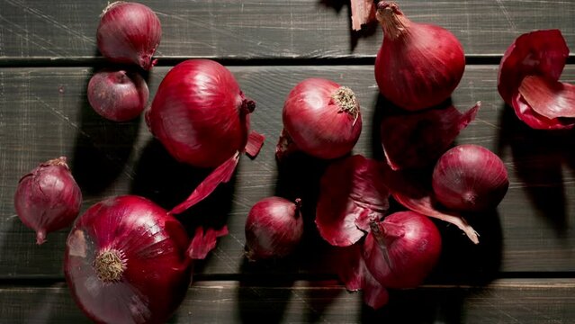 TOP VIEW: Peels fall on a red onion bulbs on a wooden dark table