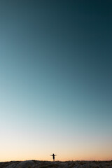 Silhouette of the person on the high rock at sunset