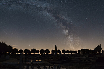 Milky Way over french cemetery with silhouette of trees at night, Normandy, France