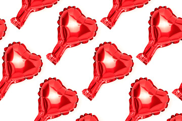 Repetitive pattern made from red heart foil balloon. Creative layout on a white background.