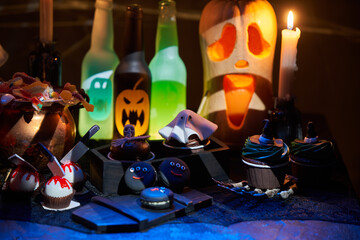Halloween pumpkins with burning mouths, candles, drinks and sweets.